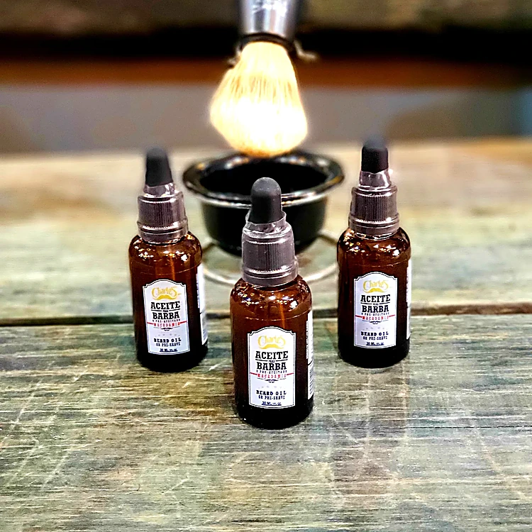 Tres frascos de aceite para barba y una brocha de afeitar sobre una tabla de madera