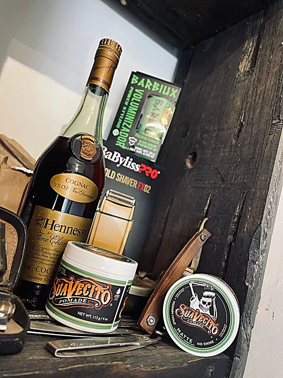 Repisa con pomadas, una máquina para cortar y botellas, junto a la ventana