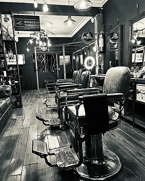 Fila de sillones de barbero antiguos con reposapiés de fierro labrado, en blanco y negro