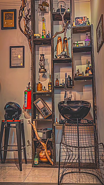 Vitrina de repisas con botellas, una lámpara de aceite y un lavacabezas negro al centro